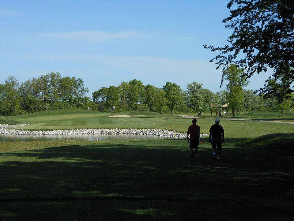 Two golfers making their way past one of the water hazards at Lorette Golf Course
